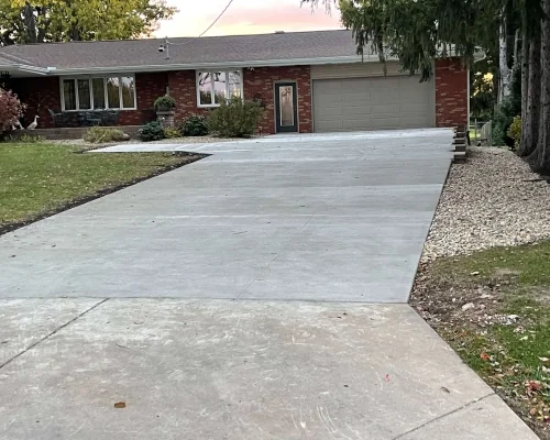 Concrete drive with landscaped beds beside a brick home