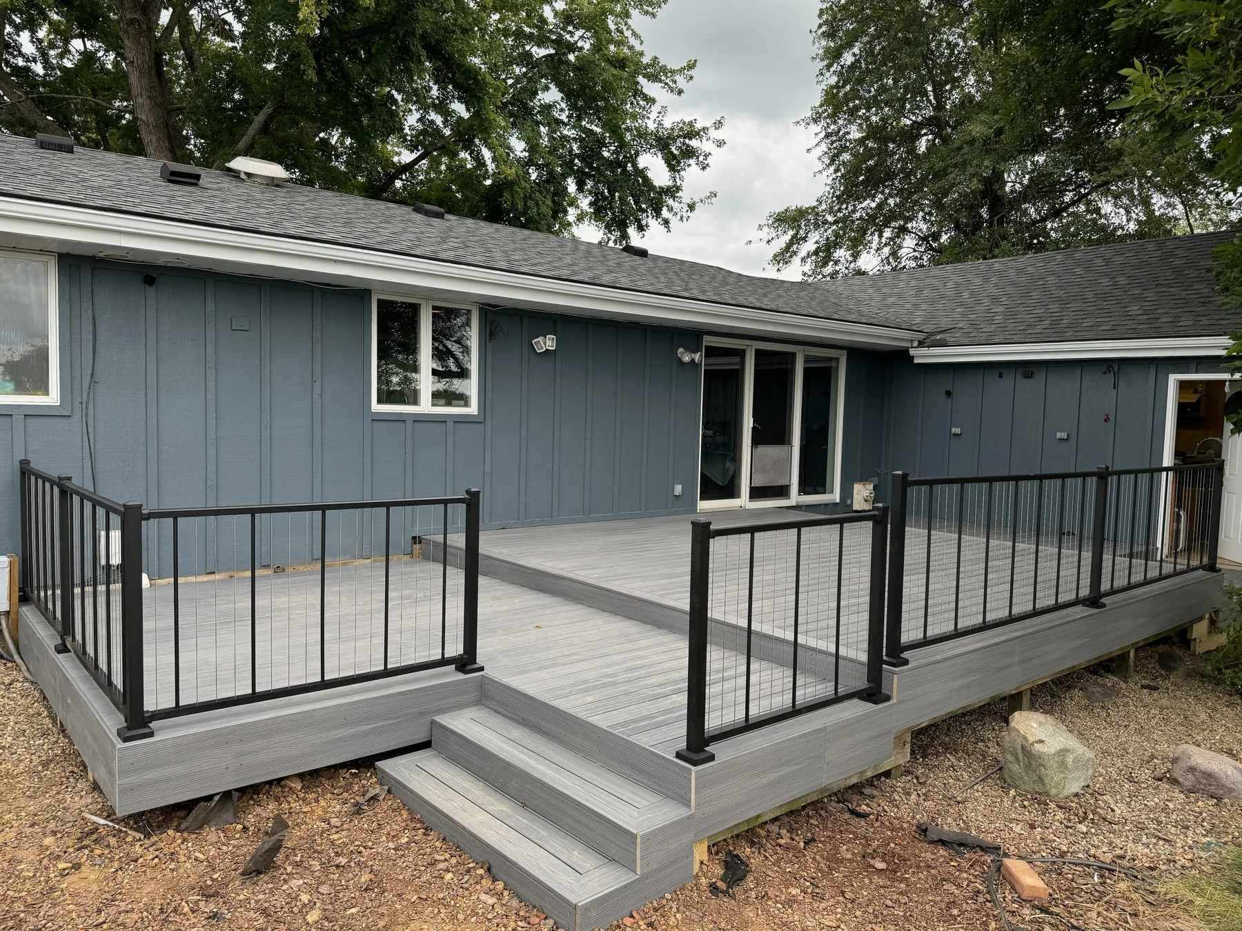 Gray composite deck with black railing behind a home