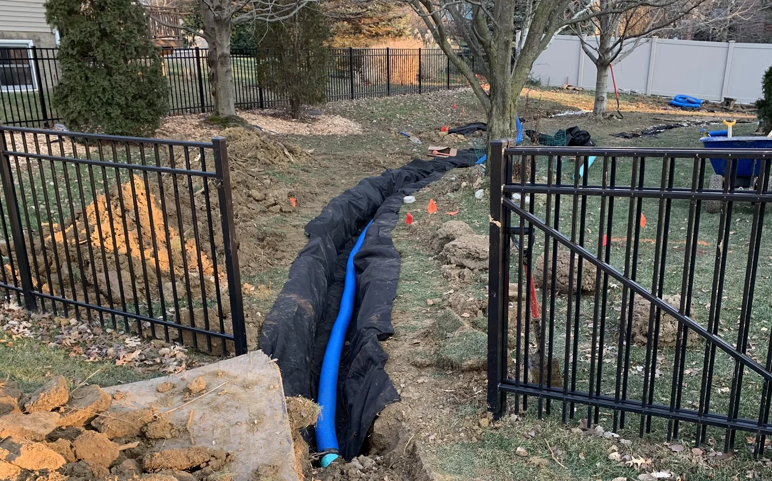 Drainage trench with pipe and stone near a fence